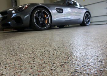a black car on a parking garage with concrete epoxy floor